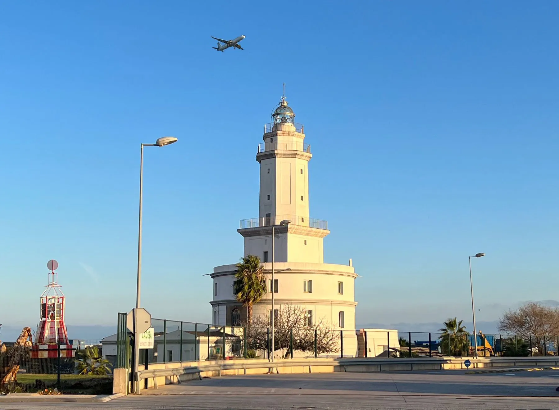 El far del Llobregat, al Prat, amb un avió travessant el cel